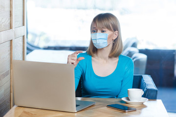 I need a little bit more. Portrait of worry woman with surgical medical mask sitting and working on laptop on video call and asking for smoething more to have. Indoor, medicine and health care concept