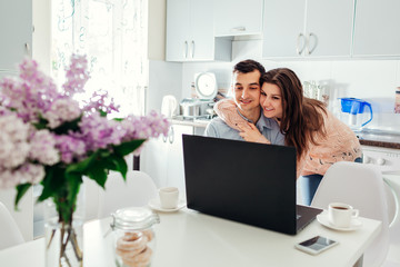 Happy young couple self isolated at home during coronavirus pandemic quarantine using laptop...