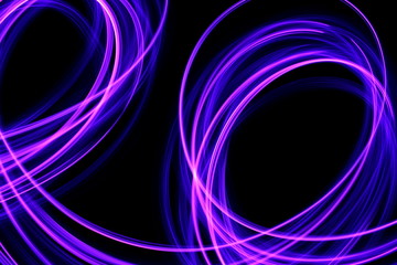 Light painting photography, long exposure photo of purple and blue streaks of vibrant color against a black background