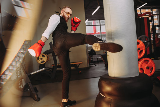 Stylish Man In A White Shirt And Black Vest Is Boxing In The Gym. Red Boxing Gloves