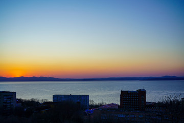 Fototapeta na wymiar Sunset on the background of the sea and urban landscape,