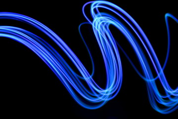 Long exposure photograph of neon blue streaks of light in an abstract swirl, parallel lines pattern...