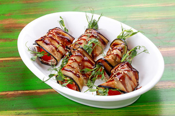 Eggplant vegetable rolls with unagi sauce. On a colored wooden background. Vegetarian dish.