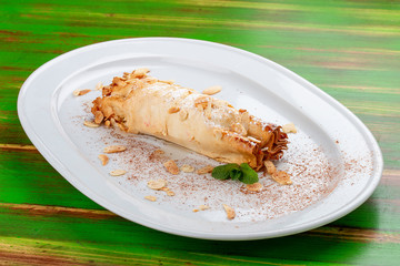 Apple strudel with peanuts. On a colored wooden background. Vegetarian dish.