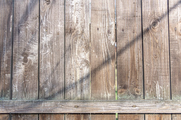 Background in grunge style. Wooden old fence with scuffs. From vertical boards of brown color. 