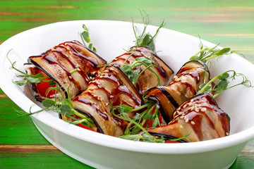 Eggplant vegetable rolls with unagi sauce. On a colored wooden background. Vegetarian dish.