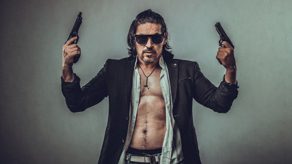 sexy muscular body model portrait of a young man holding a gun in his hands