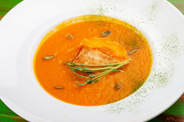Pumpkin cream soup with tofu. On a colored wooden background. Vegetarian dish.