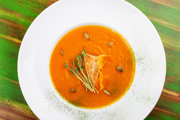Pumpkin cream soup with tofu. On a colored wooden background. Vegetarian dish.