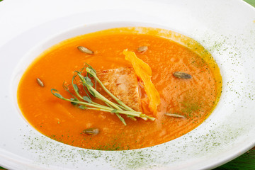Pumpkin cream soup with tofu. On a colored wooden background. Vegetarian dish.