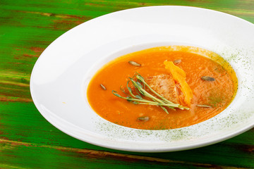Pumpkin cream soup with tofu. On a colored wooden background. Vegetarian dish.