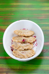 Dumplings with cherries. On a colored wooden background. Vegetarian dish.