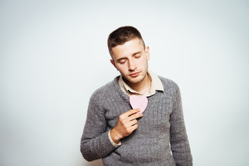 Portrait of a young man holding a large paper heart