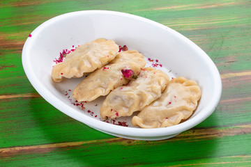 Dumplings with cherries. On a colored wooden background. Vegetarian dish.