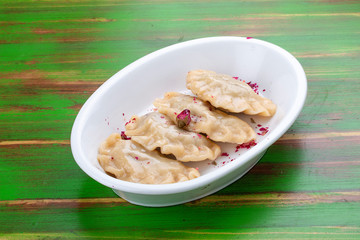 Dumplings with cherries. On a colored wooden background. Vegetarian dish.