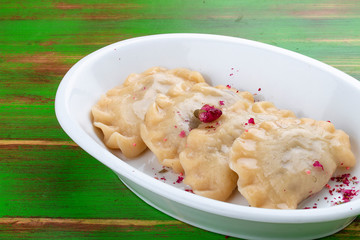 Dumplings with cherries. On a colored wooden background. Vegetarian dish.