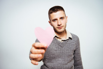 Portrait of a young man holding a large paper heart
