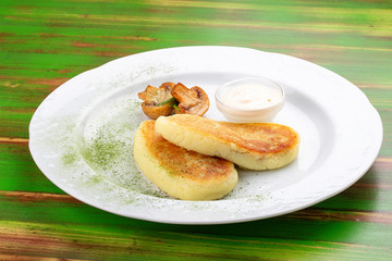 Potato zrazy with sour cream. On a colored wooden background. Vegetarian dish.