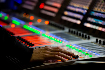 Sound engineer controls the settings on the mixing console panel in sound recording studio for music, sound recording, concert activities