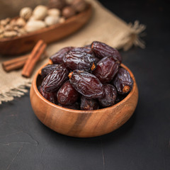dried fruit in a square wooden bowl on a dark background and burlap