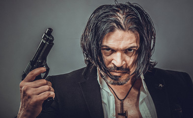 sexy muscular body model portrait of a young man holding a gun in his hands