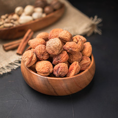 dried fruit in a square wooden bowl on a dark background and burlap
