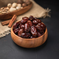 dried fruit in a square wooden bowl on a dark background and burlap