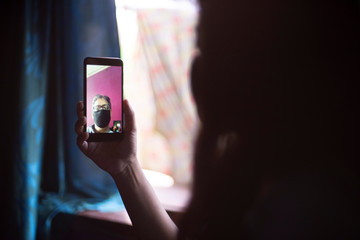 Video conferencing over phone between home isolated Indian Bengali father and daughter during corona virus quarantine period using face masks. Indian lifestyle and pandemic effect
