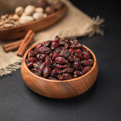 dried fruit in a square wooden bowl on a dark background and burlap