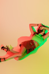 top view of attractive, trendy girl lying with closed eyes on yellow background with green and red shadows