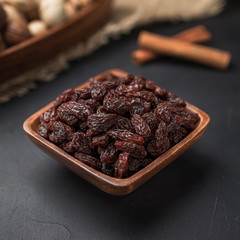 dried fruit in a square wooden bowl on a dark background and burlap