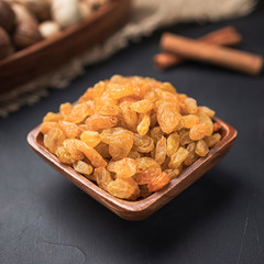 dried fruit in a square wooden bowl on a dark background and burlap
