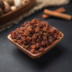 dried fruit in a square wooden bowl on a dark background and burlap