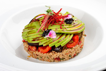 Salad with quinoa, avocado and roasted vegetables.  On a colored wooden background. Vegetarian dish.