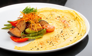 Hummus with baked vegetables.  On a black  background. Vegetarian dish.