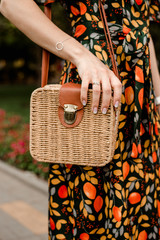 young woman holding a straw purse. small straw bag in hands. girl's hand holding a small clutch. summer accessories. summer fashion