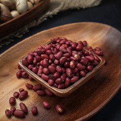 nuts on a square wooden bowl and an oval wooden tray on a dark background and burlap