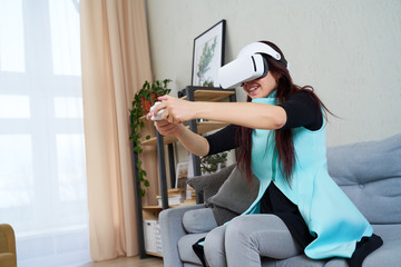 Woman with virtual reality headset and gamepad is playing game.