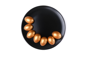 Minimal easter concept. Stylish Easter golden decorated eggs on black plate isolated on white background. Flat lay trendy easter. Happy Easter card with copy space for text.