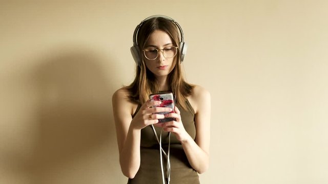 young millennial woman in glasses listening to music while shooting herself on the phone