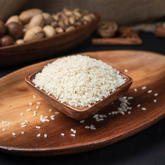 cereals and grains on a square wooden bowl and oval wooden tray on a dark background and burlap