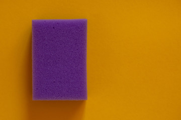 The concept of cleaning and washing. Purple sponge for cleaning on a yellow background.
