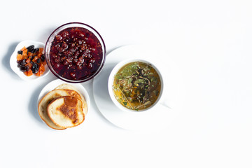 Herbal tea, raspberry jam, fritters, dry fruits on white background