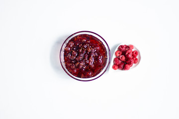 Raspberry jam and fresh berries in   bowls on white background