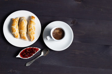 white cup of coffee, raspberry jam and cake on black wooden table