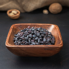 spices seasonings and grains on a square wooden bowl on a dark background and burlap