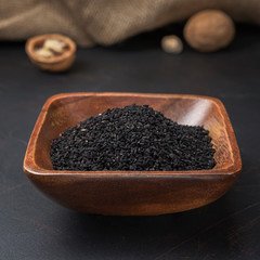 spices seasonings and grains on a square wooden bowl on a dark background and burlap