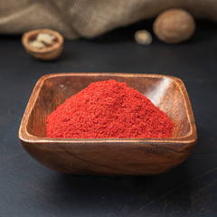 spices seasonings and grains on a square wooden bowl on a dark background and burlap