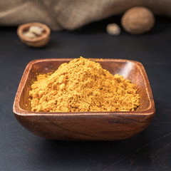 spices seasonings and grains on a square wooden bowl on a dark background and burlap