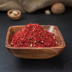 spices seasonings and grains on a square wooden bowl on a dark background and burlap